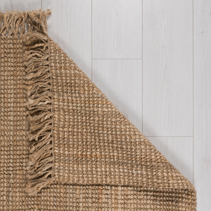 l'angle du tapis en jute naturel est replié afin de montrer le détail de la matière sous le tapis