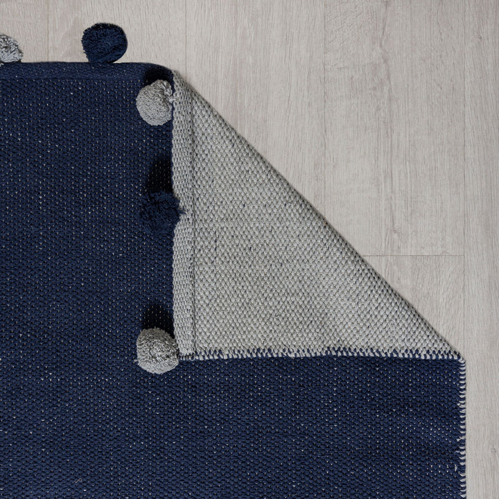 angle du tapis pompom bleu plié pour voir le dessous du tapis#couleur_bleu